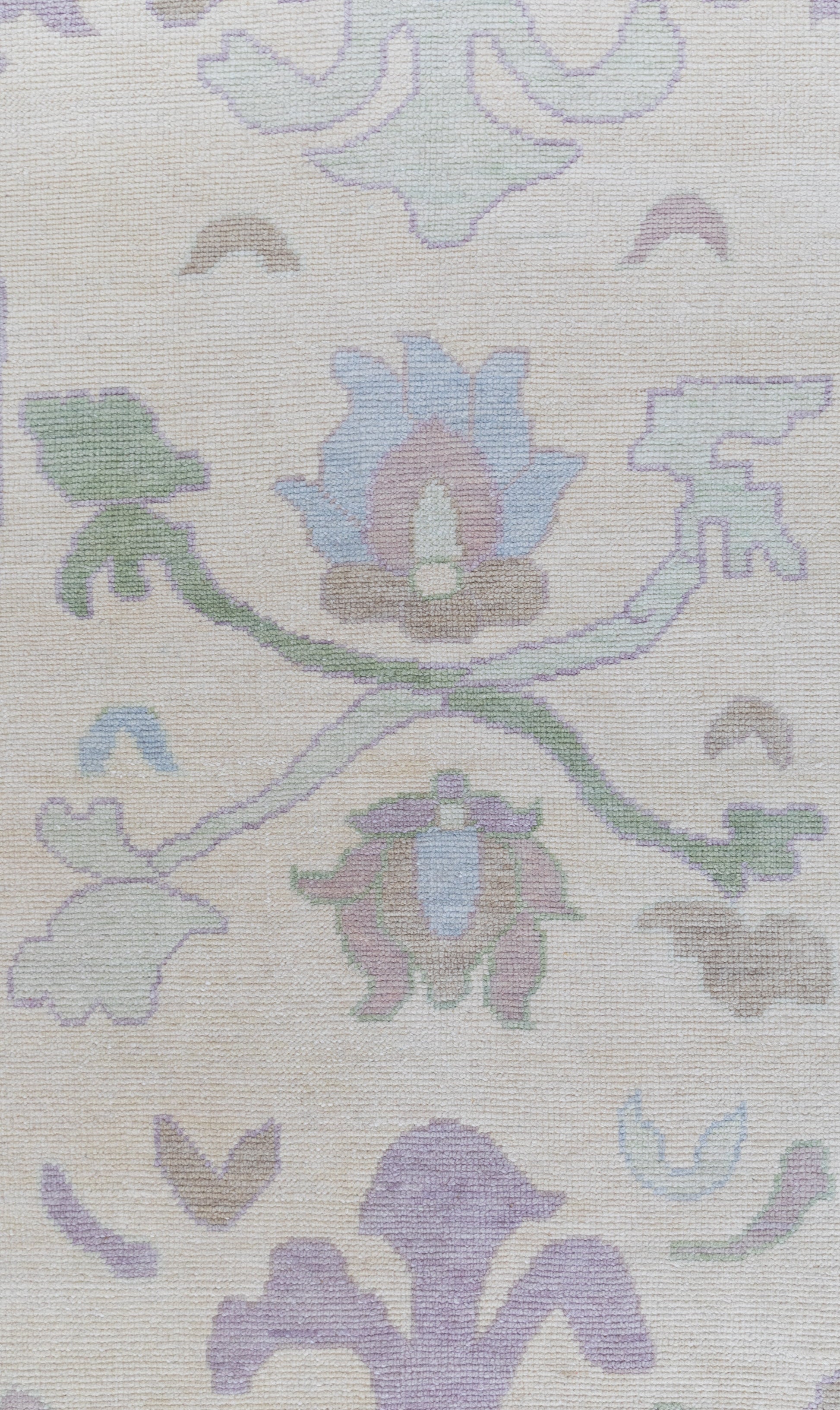 A section of a modern Oushak rug featuring floral patterns in beige, lavender, and light blue colors.