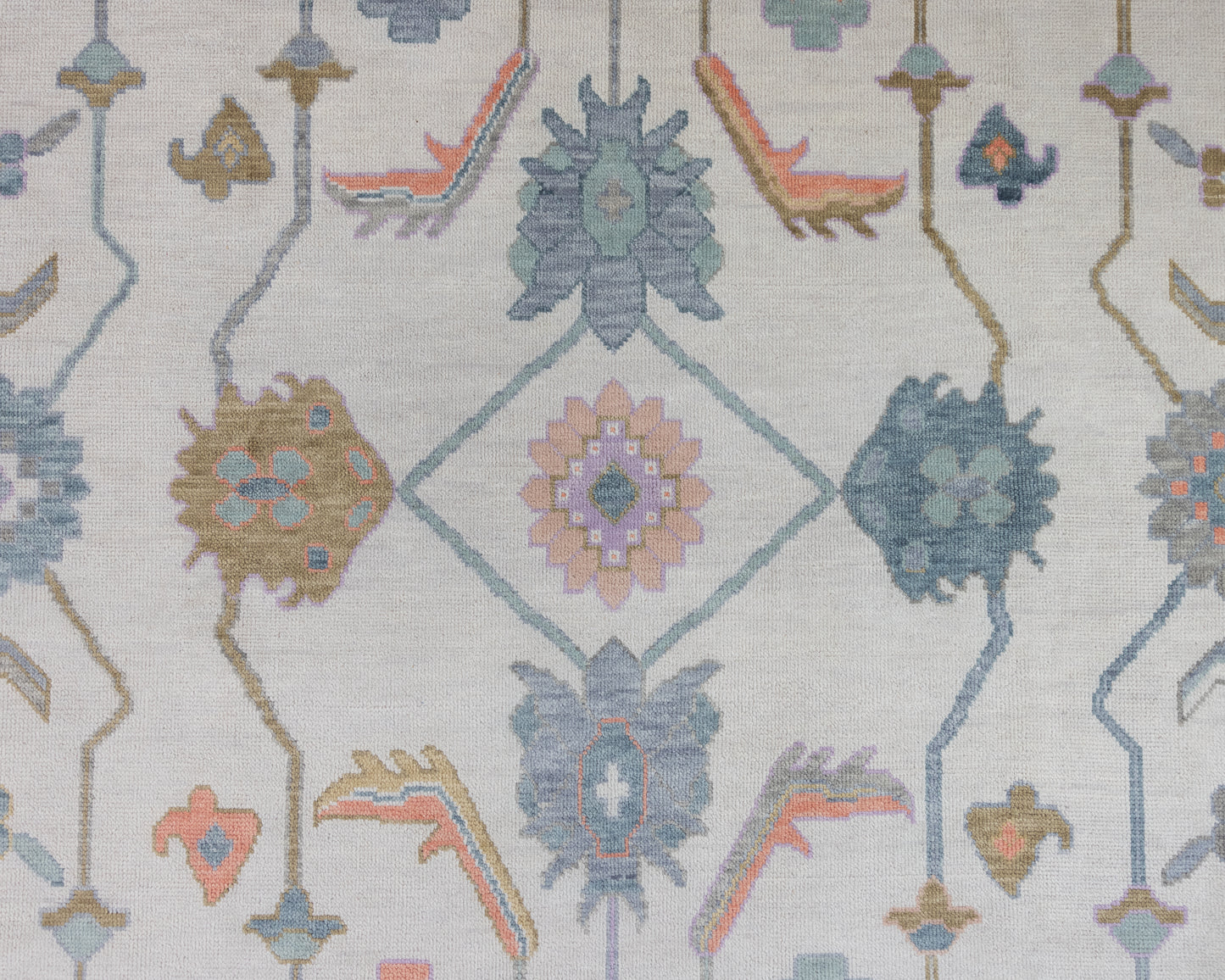 Close-up view of a Jolene Modern Oushak Rug featuring a traditional geometric pattern with melon, teal, marigold, and coral colors on a cool stone ground.