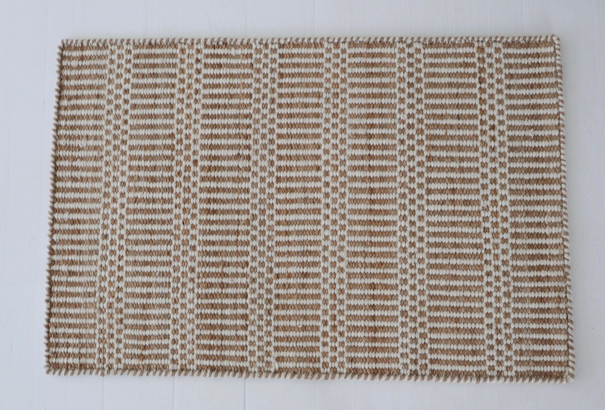 Textured brown and beige woven rug on a white background