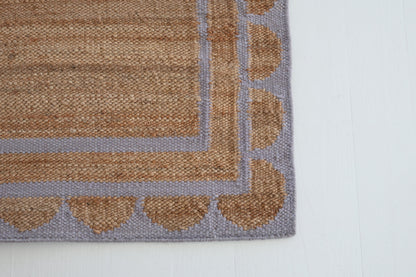 Jute and wool rug with lilac scalloped edge, handwoven for natural elegance.