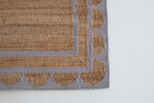 Jute and wool rug with lilac scalloped edge, handwoven for natural elegance.