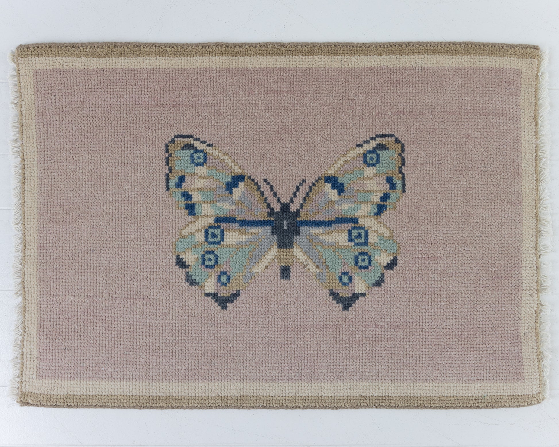 Hand-knotted wool rug featuring a butterfly motif on a soft mauve background with ivory border – Mauve Butterfly Mini Rug by Locust Lane Rugs