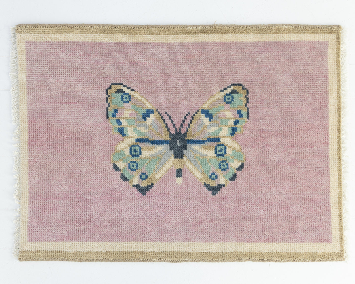 Hand-knotted wool rug featuring a butterfly motif on a blush pink background with ivory border – Pink Butterfly Mini Rug by Locust Lane Rugs