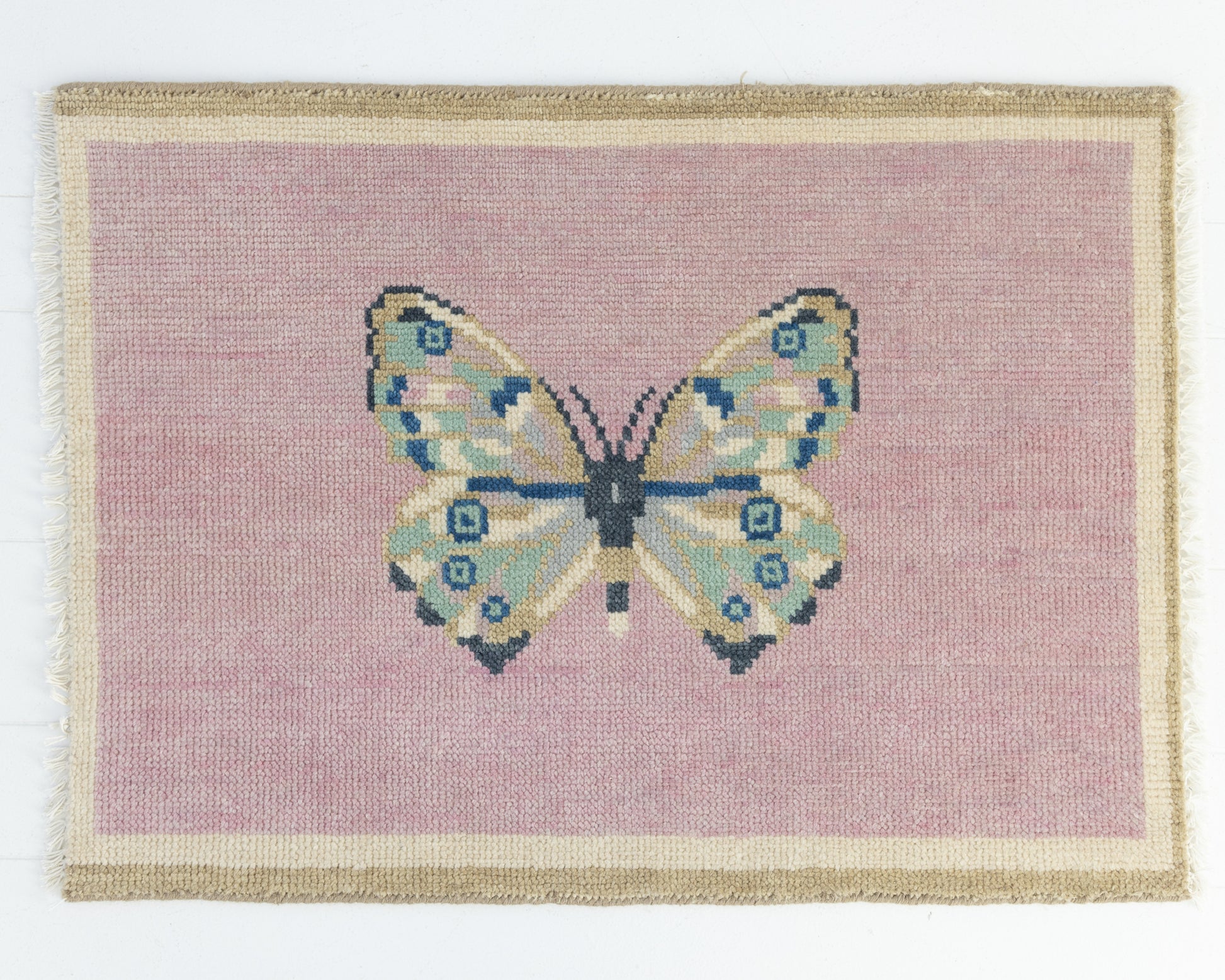 Hand-knotted wool rug featuring a butterfly motif on a blush pink background with ivory border – Pink Butterfly Mini Rug by Locust Lane Rugs