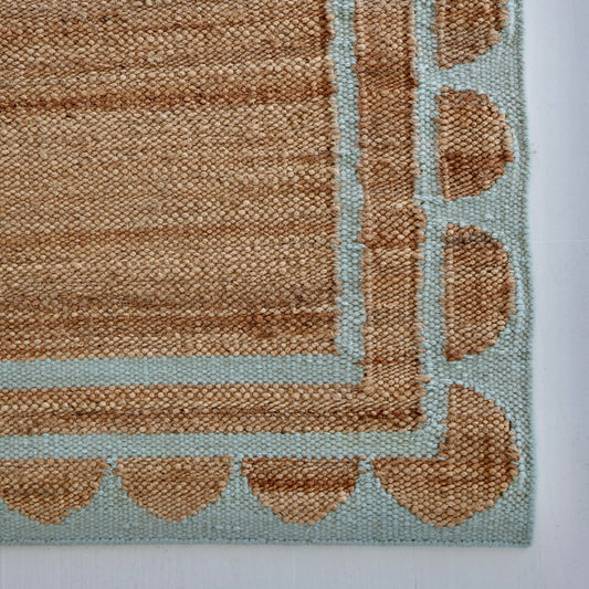 Handwoven jute and wool rug in natural tones with a sea blue scalloped border – Sea Cliff Blue Scalloped Edge Rug by Locust Lane Rugs