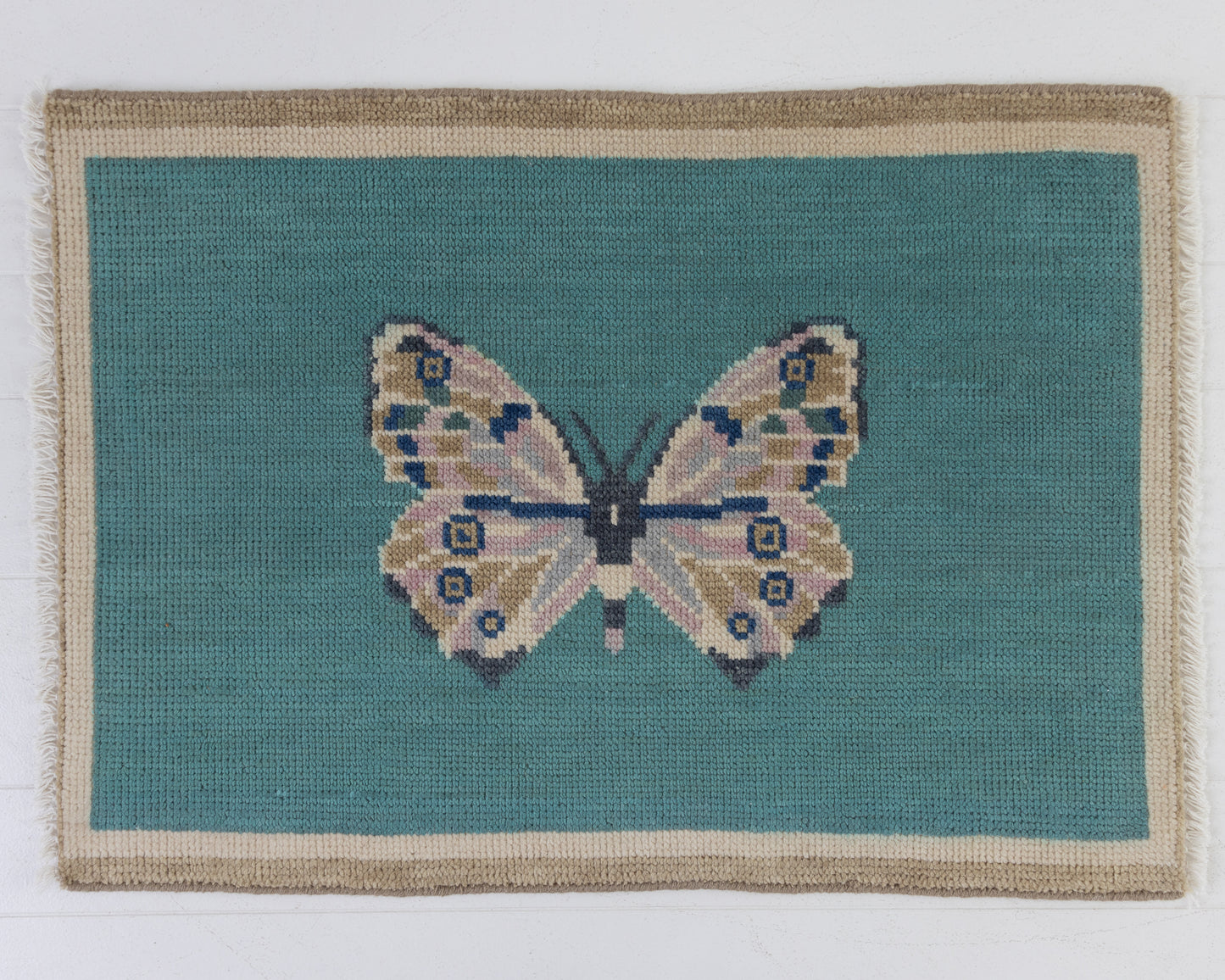 Hand-knotted wool rug featuring a butterfly motif on a turquoise background with ivory border – Turquoise Butterfly Mini Rug by Locust Lane Rugs